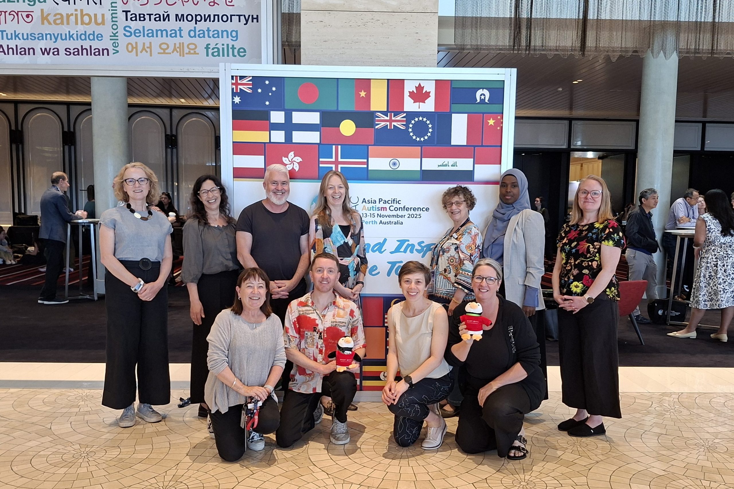a group of researchers and professional staff standing and kneeling in front of a sign