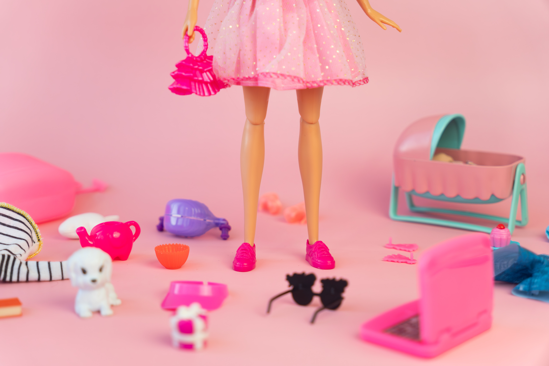 Barbie doll in a pink dress on a pink background. various accessories for playing with a doll.
