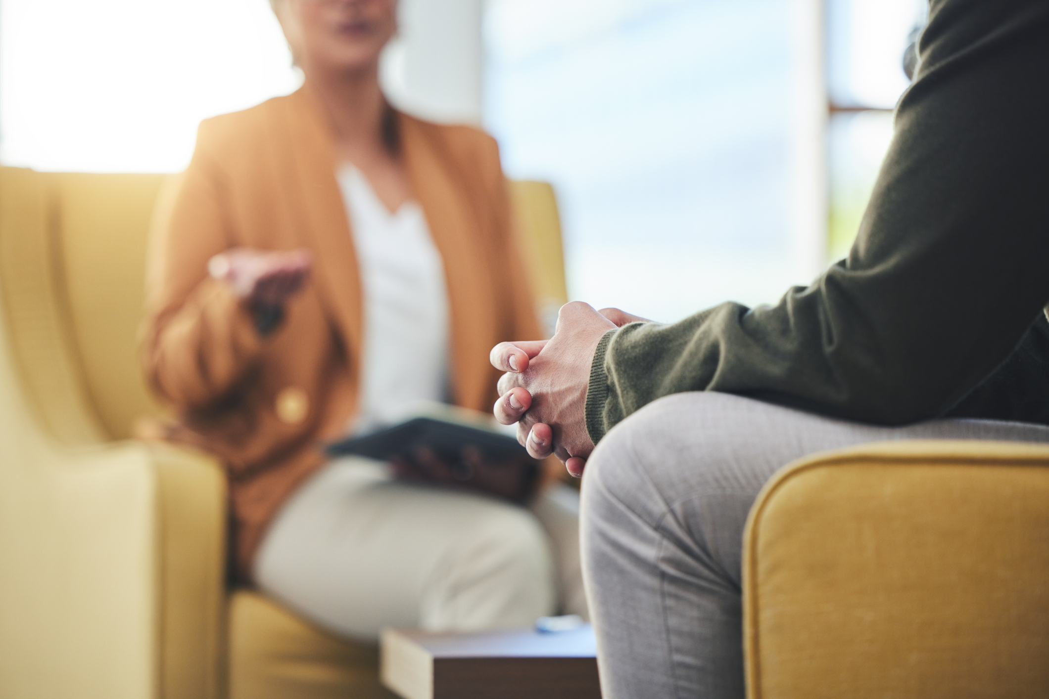 two people seated in chairs having a conversation in a therapist office