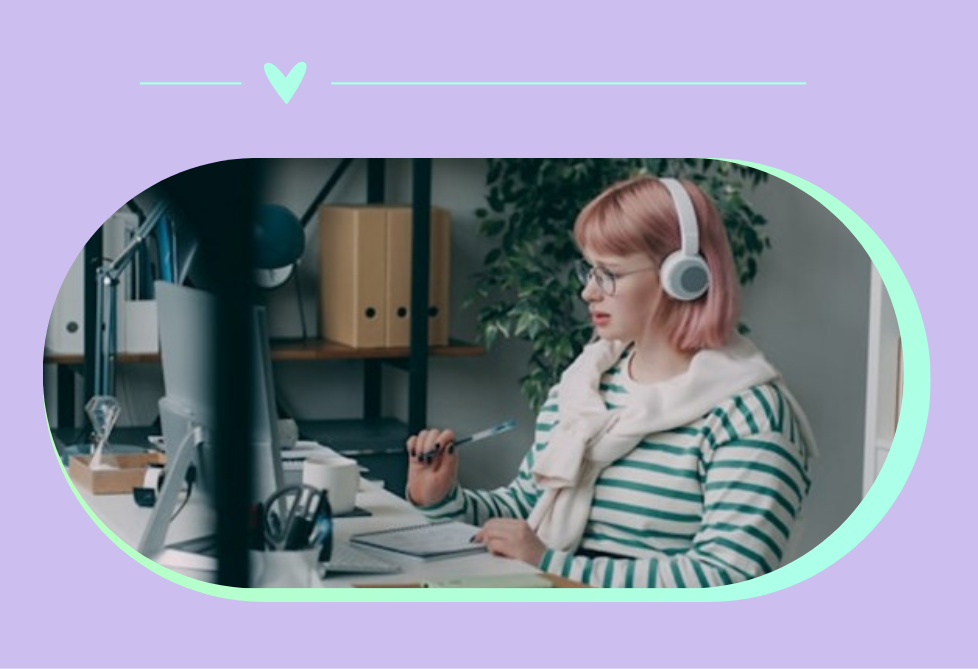 image of female working in an office at a computer, wearing headphones
